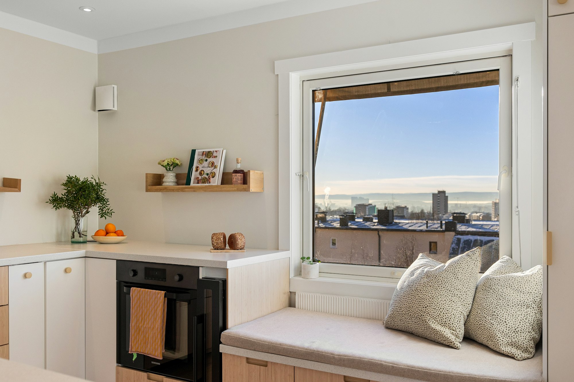 Gepolsterte Fensterbank neben einer Küche mit Blick über die Stadt